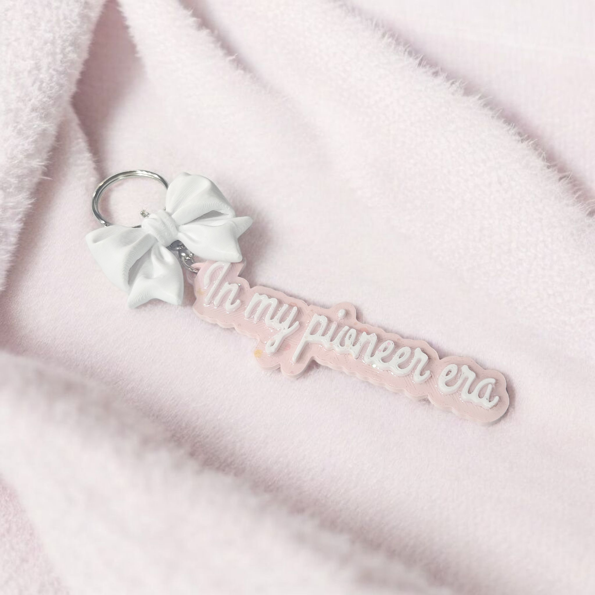 Pastel pink “In My Pioneer Era” 3D-printed keychain with iridescent glitter UV resin and matching 3D-printed bow charm