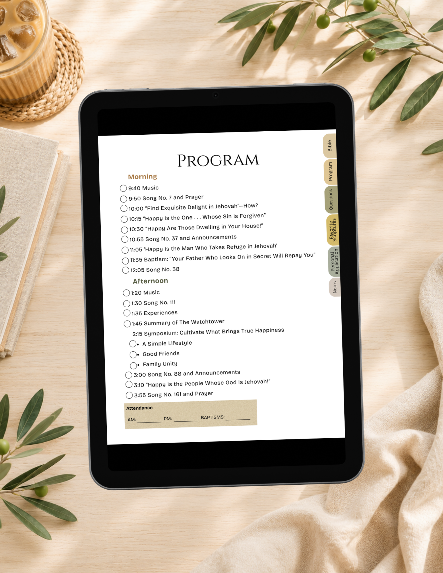 A tablet device displaying a digital program or checklist interface, placed on a beige fabric surface with decorative leaves, a woven basket, and a candle visible around it.