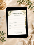 A tablet lying on a beige fabric surface, displaying a printable or digital planner page titled "Scriptures to Treasure" with lined writing areas and small decorative botanical borders. The scene is styled with olive leaves, a woven coaster, a notebook, and draped fabric.