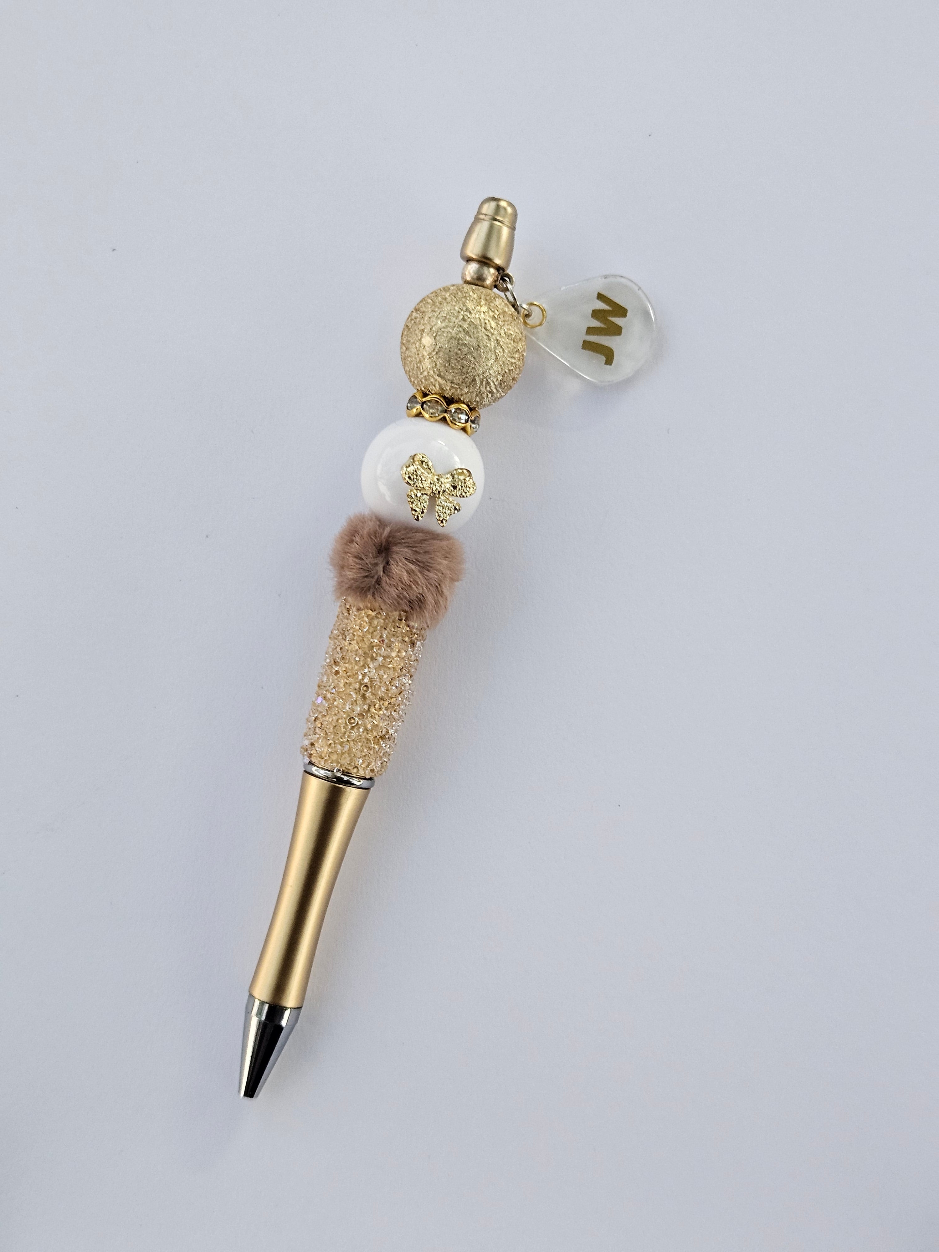 Decorative pen with gold and white accents on a light gray background