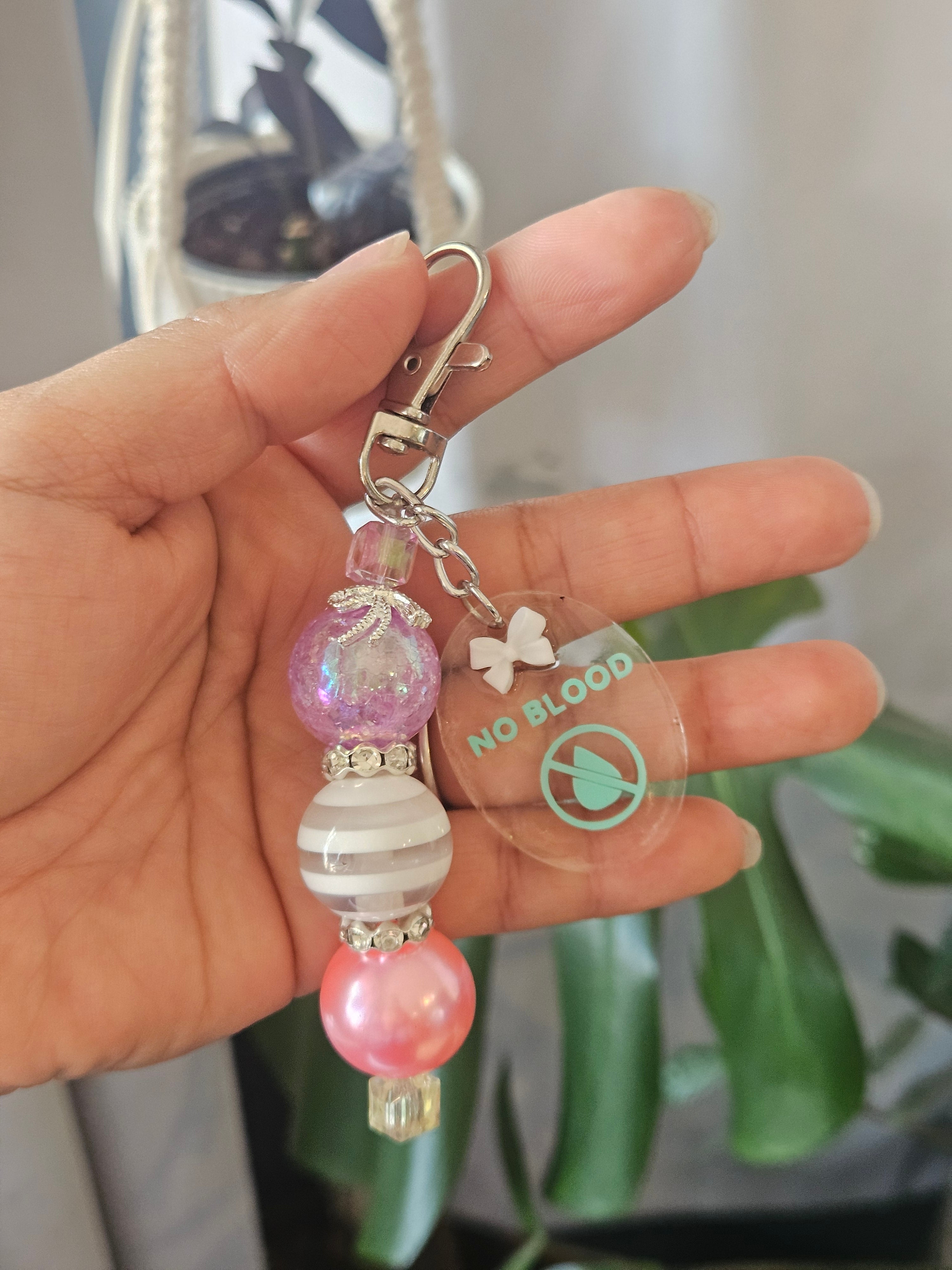 Jw no blood keychain  holding and against blurred background