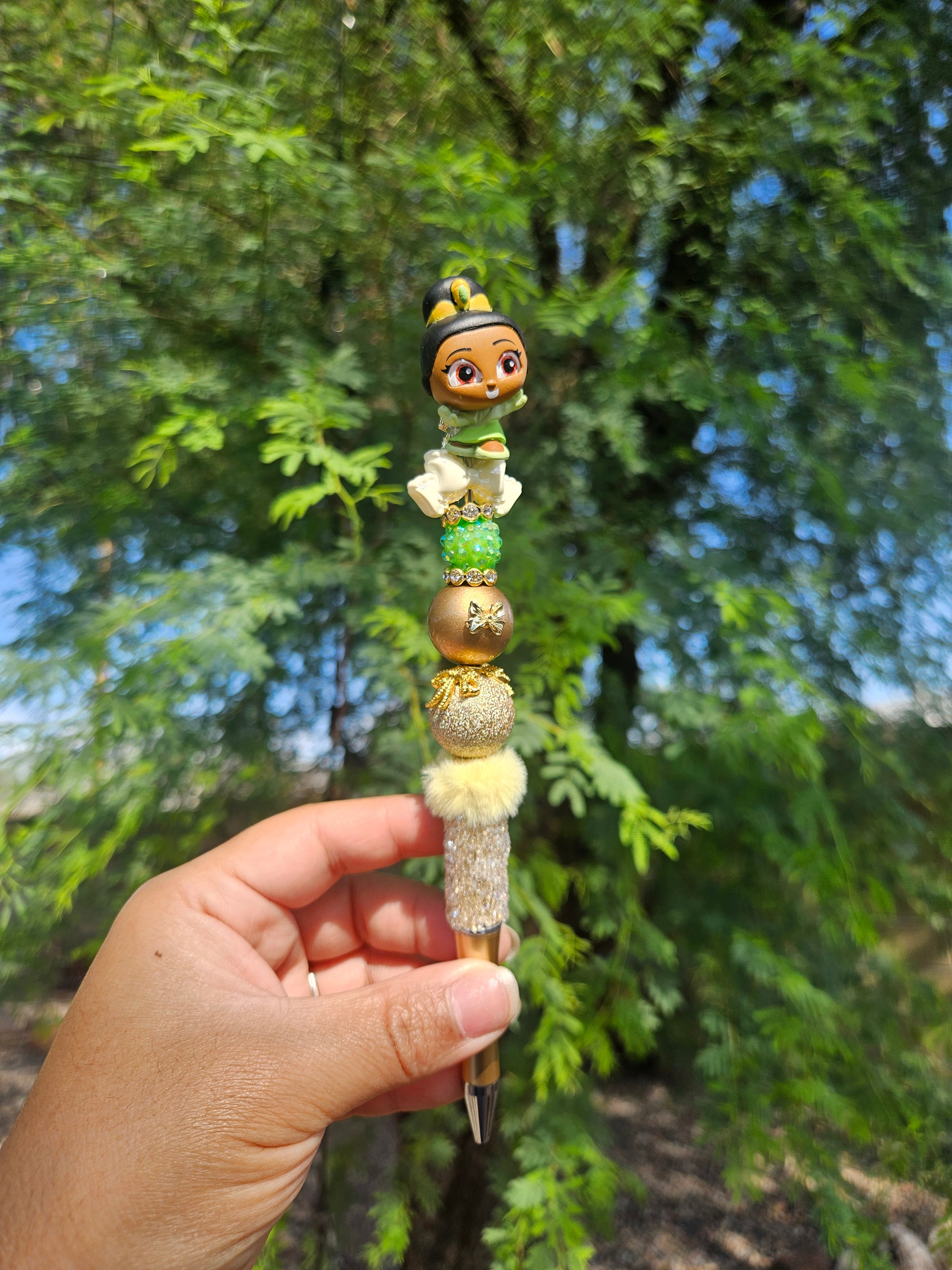 Princess Tiana beadable ped, beaded pen, gold beaded pen with green foliage background