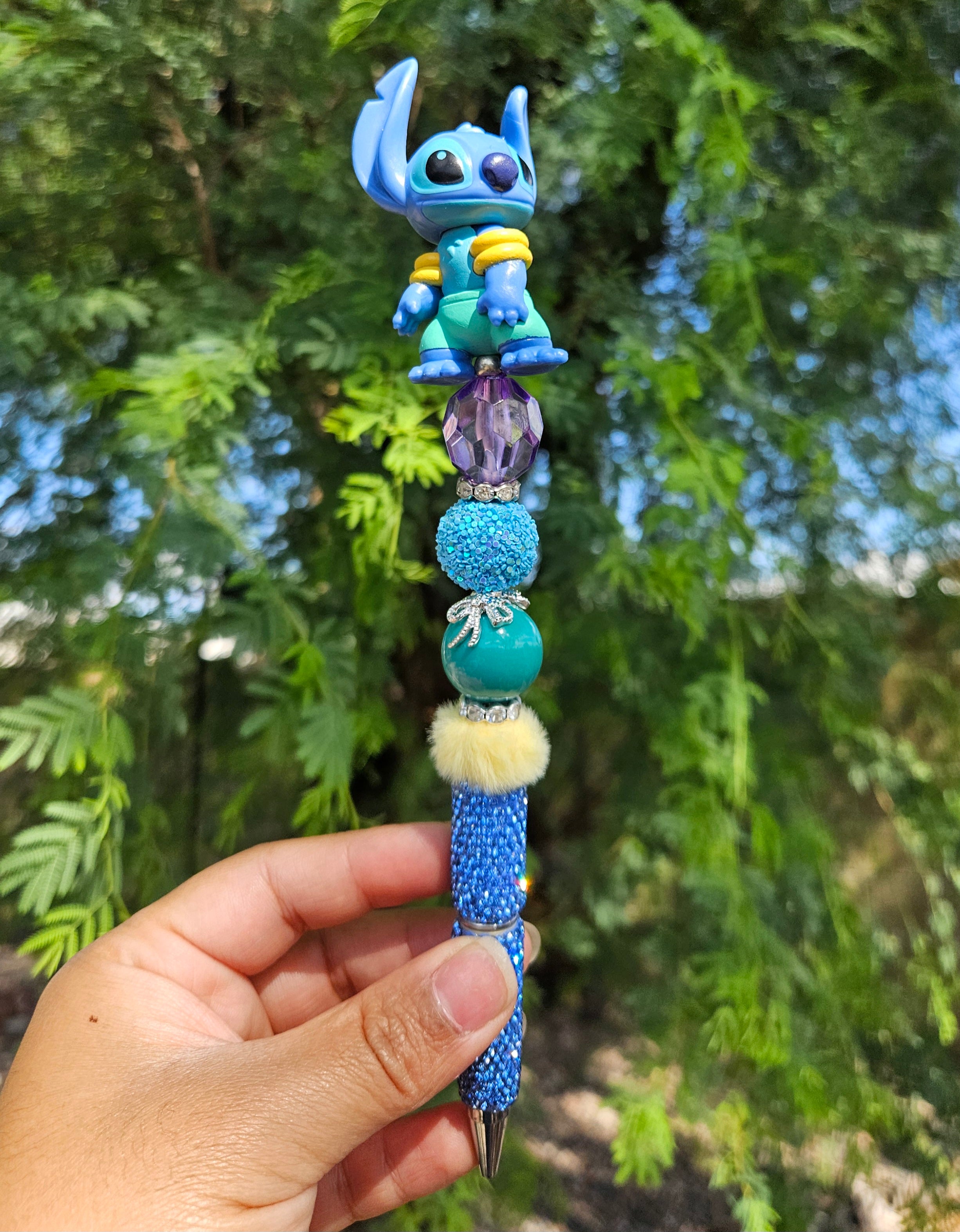 Decorative pen with a blue character figure held in front of green foliage