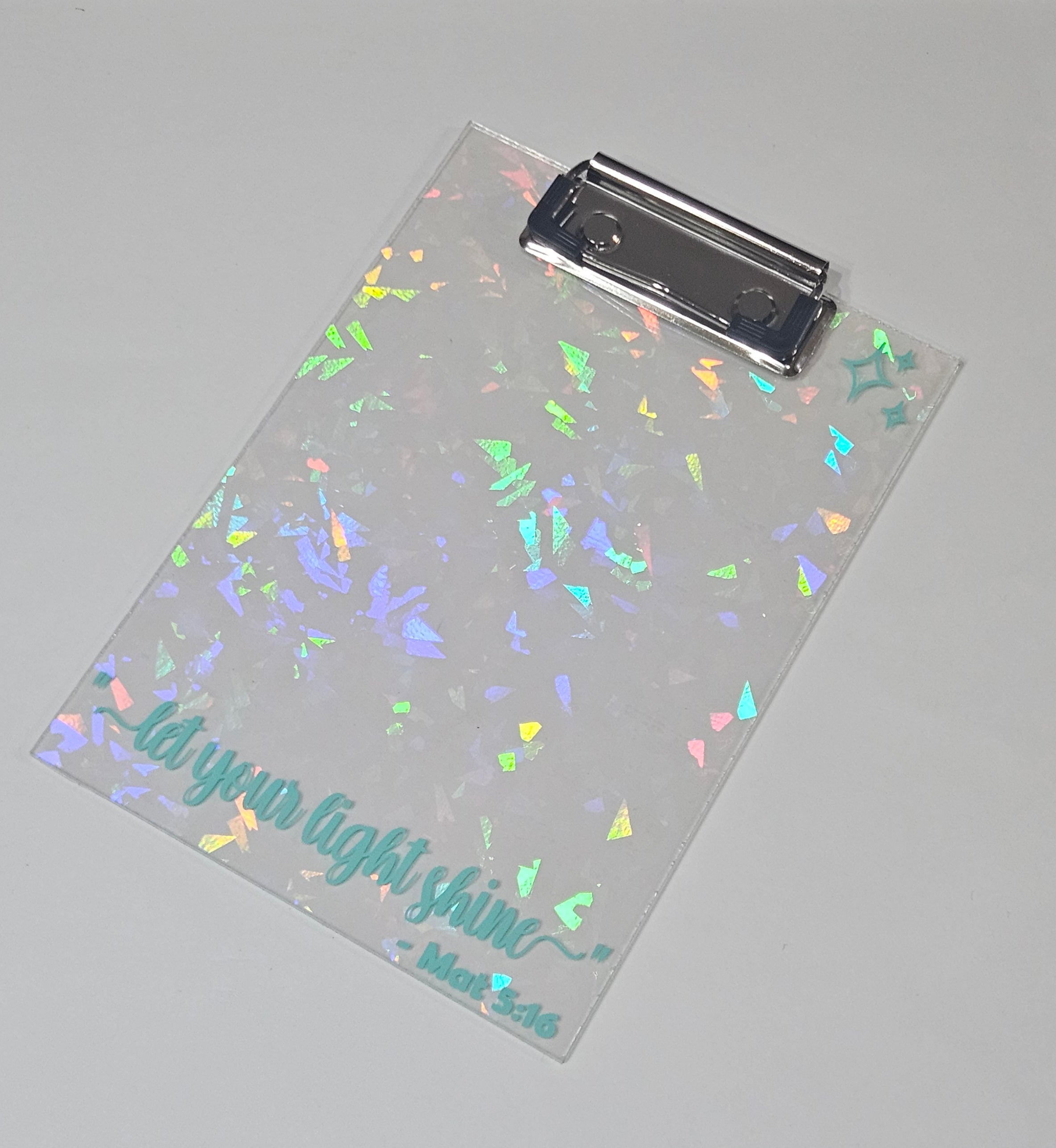 "let your light shine" Clear clipboard with colorful confetti pattern and text on a gray background