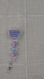 Hand-poured circle-shaped glitter resin badge reel with “Keep Calm and Trust Jehovah” message, iridescent glitter and pink & blue accent beads, for JW pioneers video